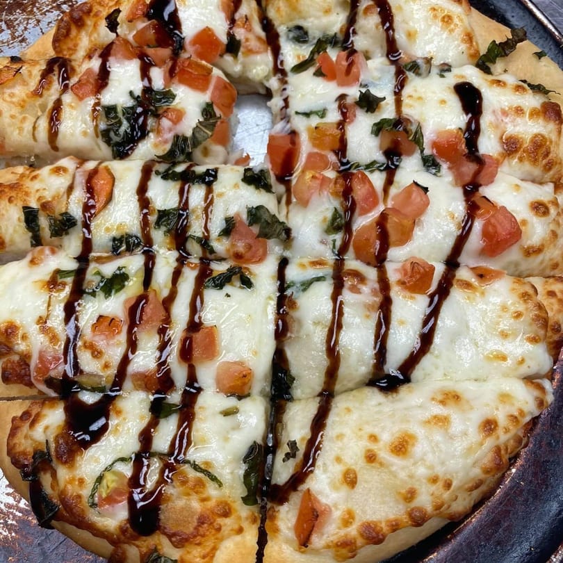 Rego's Brickhouse Pizza's cheesy breadsticks with diced tomatoes, basil, and balsamic glaze.