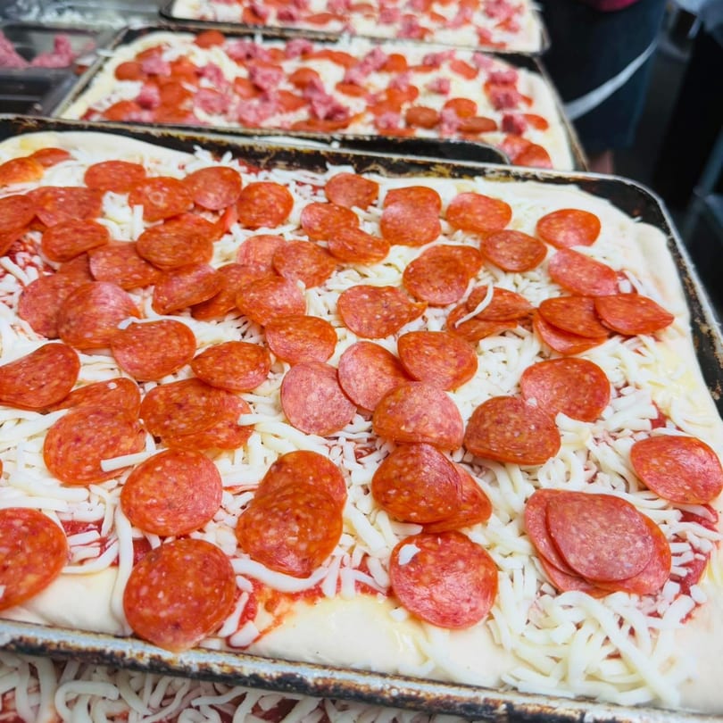 Multiple rectangular Rego's Brickhouse pizzas topped with pepperoni and shredded mozzarella cheese.